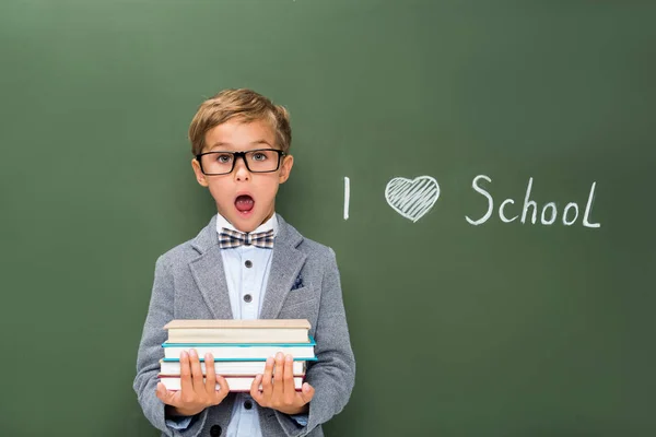 Schockierter Schüler mit Bücherstapel — Stockfoto