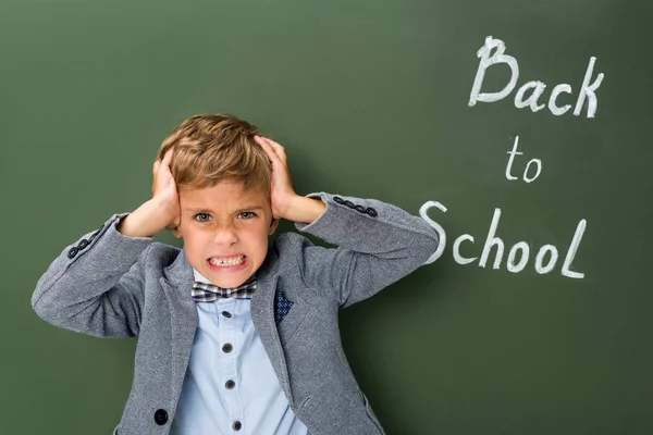 Colegial enojado sosteniendo su cabeza - foto de stock