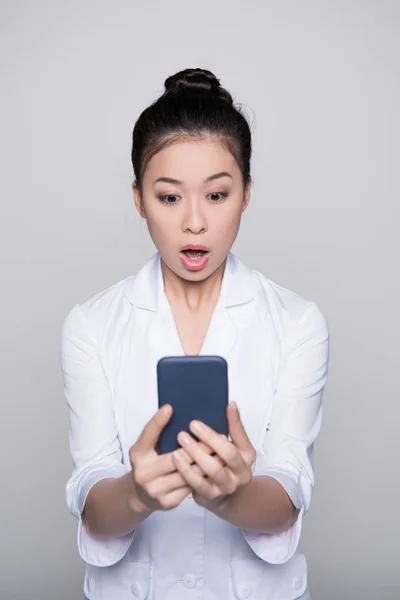 Enfermera joven mirando el teléfono inteligente - foto de stock