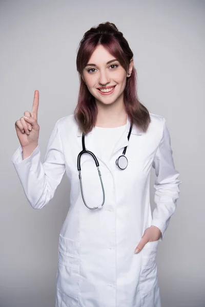 Jeune femme médecin levant doigt — Photo de stock