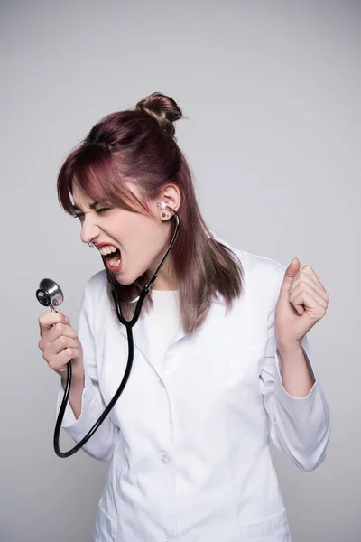 Jeune femme médecin chantant dans stéthoscope — Photo de stock