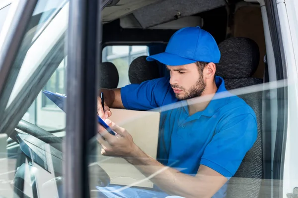 Delivery man filling in documents — Stock Photo