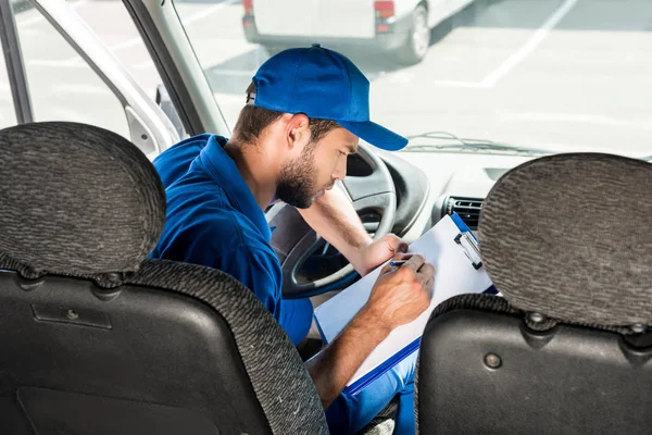 Entrega hombre escribiendo en portapapeles - foto de stock