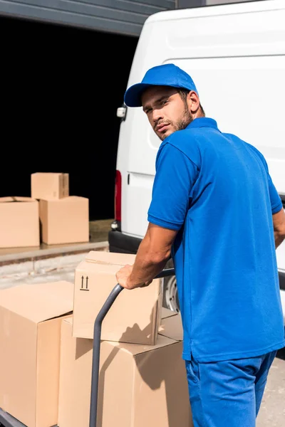 Delivery man driving cart with boxes — Stock Photo