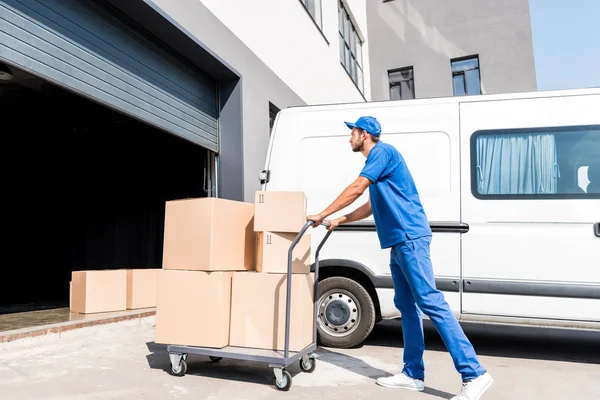 Hombre de entrega con cajas en el carrito - foto de stock