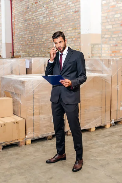 Businessman talking by phone at warehouse — Stock Photo