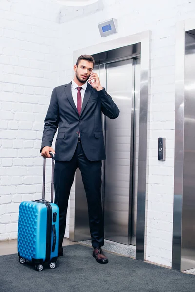 Hombre de negocios con maleta al lado del ascensor - foto de stock