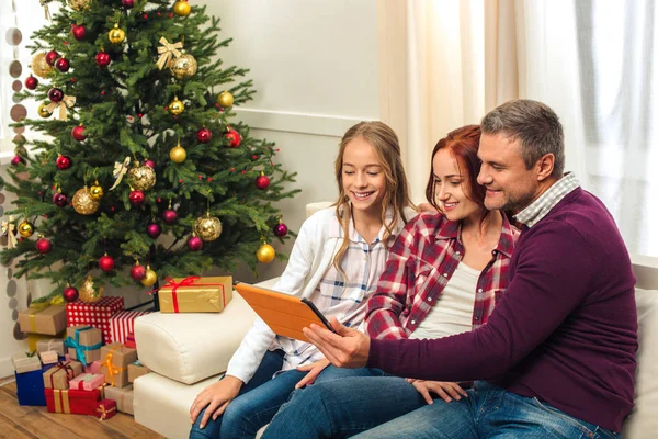 Familia con tableta digital en la noche de Navidad - foto de stock