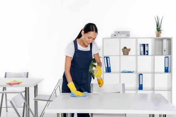 Young cleaner wiping table — Stock Photo