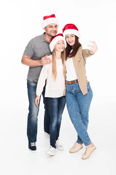 Familia en sombreros de santa tomando selfie - foto de stock