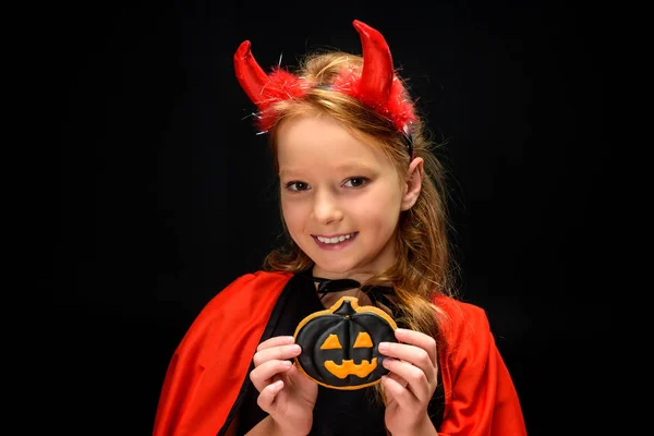 Little devil with halloween pumpkin cookie — Stock Photo