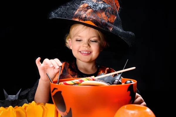 Pequeña bruja con dulces de halloween - foto de stock