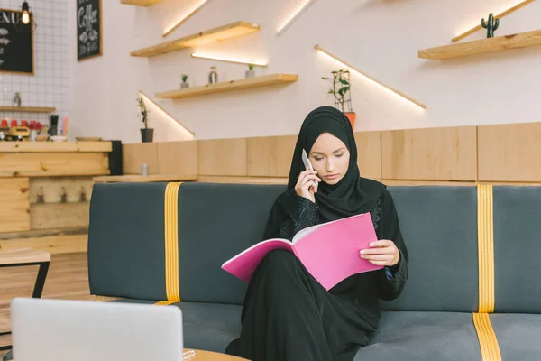 Mulher muçulmana leitura revista no café — Fotografia de Stock