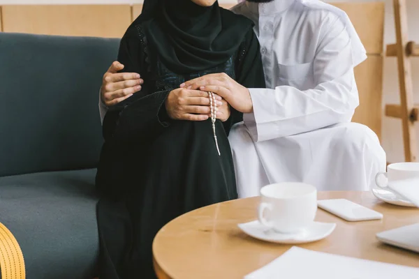 Pareja musulmana abrazándose en un sofá acogedor - foto de stock