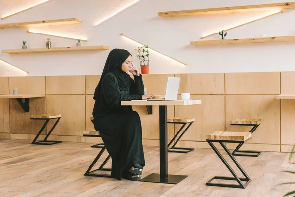Muslim woman using laptop in cafe — Stock Photo
