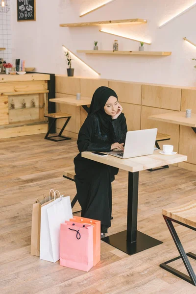 Мусульманська жінка використовує ноутбук у кафе — стокове фото