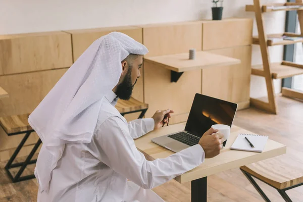 Homme musulman dans un café avec ordinateur portable — Photo de stock