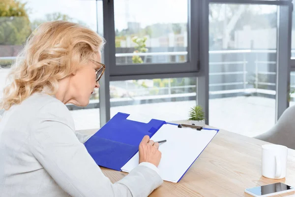 Femme d'affaires travaillant avec presse-papiers — Photo de stock