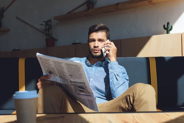 Hombre con teléfono inteligente leer periódico - foto de stock