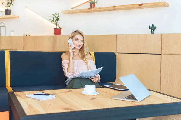 Donna con giornale che parla su smartphone — Foto stock