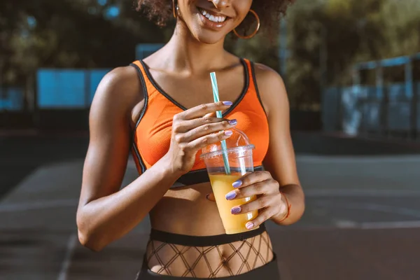 Atlética afroamericana mujer bebiendo jugo - foto de stock