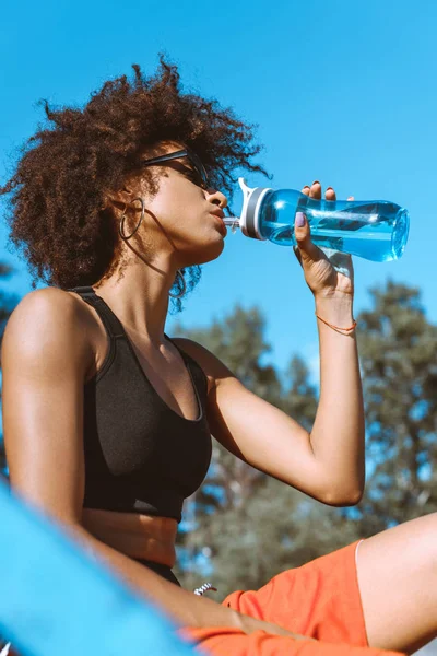 Mulher afro-americana bebendo de garrafa de água — Fotografia de Stock