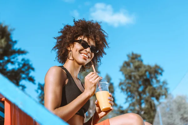 African-american woman in bleachers with juice — Stock Photo