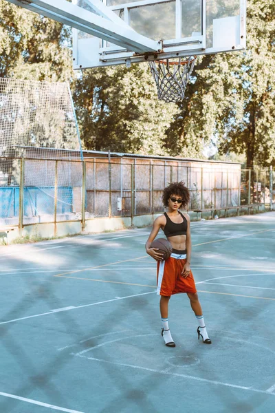 Frau in Sportbekleidung und High Heels auf dem Sportplatz — Stockfoto