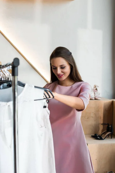 Jovem mulher escolhendo roupas em boutique — Fotografia de Stock