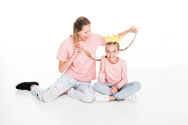 Madre sosteniendo trenzas de hija - foto de stock