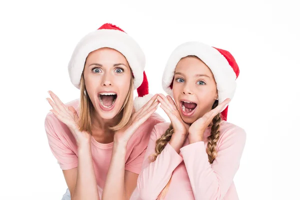 Madre e hija emocionadas en sombreros de santa - foto de stock