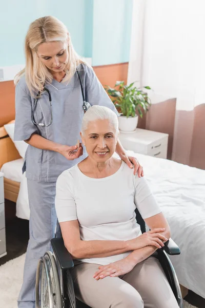 Enfermeira e mulher idosa em cadeira de rodas — Fotografia de Stock