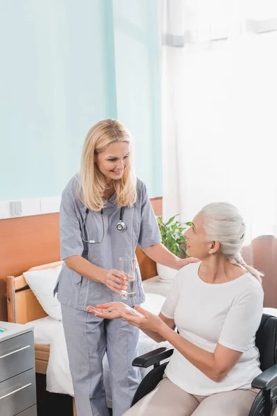 Infirmière et femme âgée en fauteuil roulant — Photo de stock