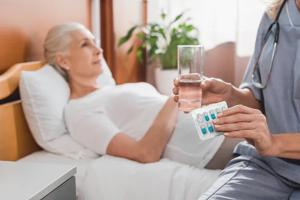 Enfermera dando medicamentos al paciente mayor - foto de stock