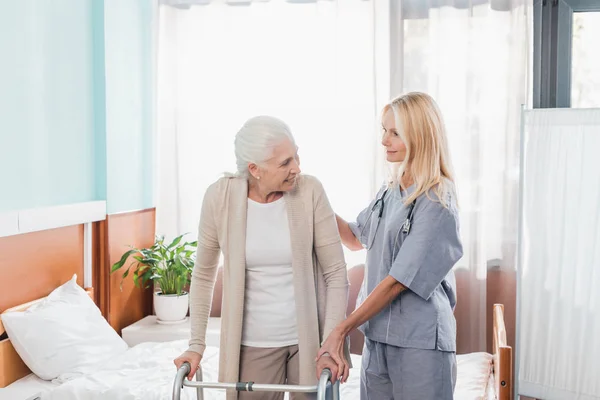 Enfermera y paciente sénior con andador - foto de stock