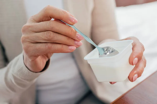 Senior woman eating yogurt — Stock Photo