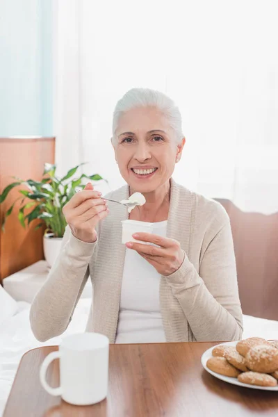 Senior woman eating yogurt — Stock Photo