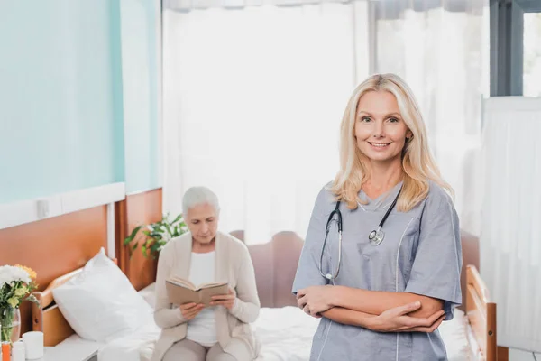 Krankenschwester und Seniorin mit Buch — Stockfoto