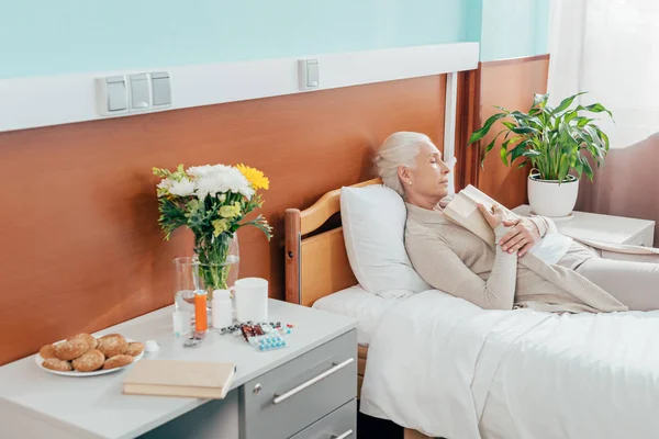 Mujer mayor con libro en el hospital - foto de stock