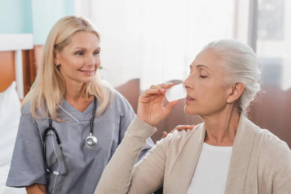 Nurse giving medicine to senior patient — Stock Photo