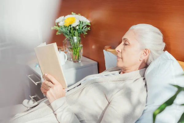 Mujer mayor con libro en el hospital - foto de stock