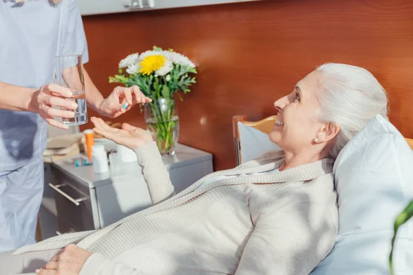 Enfermera dando medicamentos al paciente mayor - foto de stock