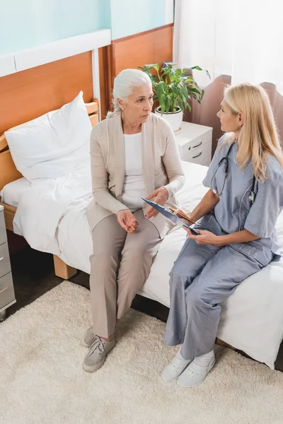 Senior woman and nurse with clipboard — Stock Photo