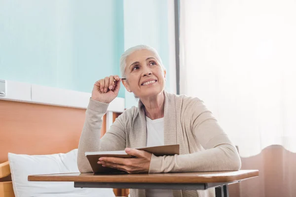 Mulher idosa com caderno no hospital — Fotografia de Stock