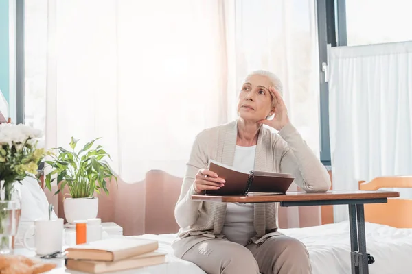 Mujer mayor con cuaderno en el hospital - foto de stock
