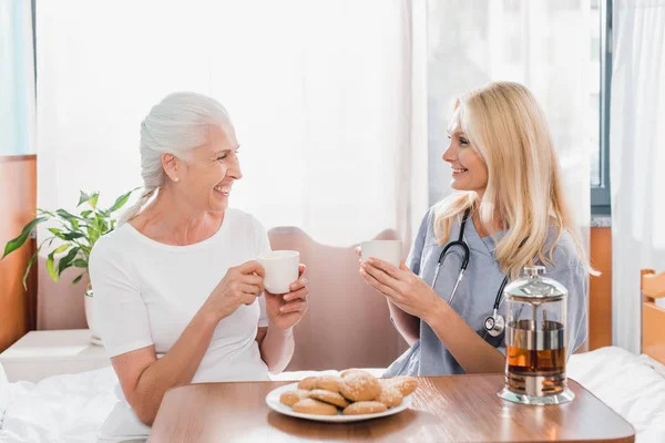 Enfermera y paciente tomando té - foto de stock