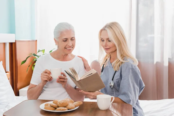 Krankenschwester und Patient lesen Buch — Stockfoto