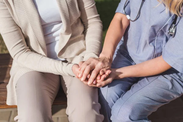 Enfermera y paciente tomados de la mano - foto de stock