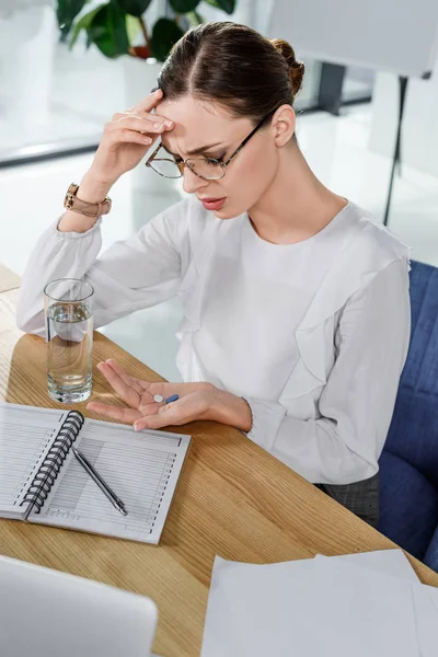 Businesswoman taking headache pills — Stock Photo