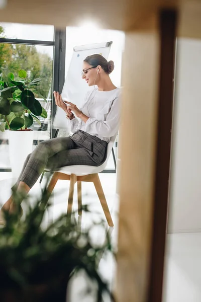 Businesswoman in earphones using smartphone — Stock Photo